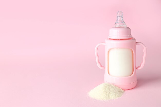 Concept d'aliments pour bébés avec du lait en poudre sur fond rose