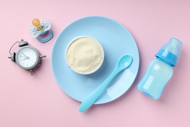 Concept d'aliments pour bébés avec du lait en poudre sur fond rose