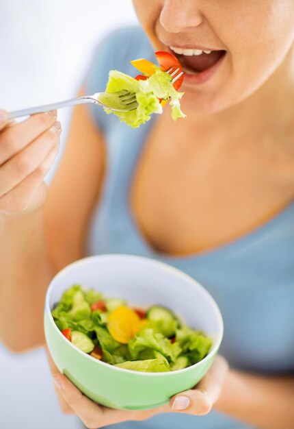 concept d'aliments sains et de cuisine - femme mangeant de la salade avec des légumes