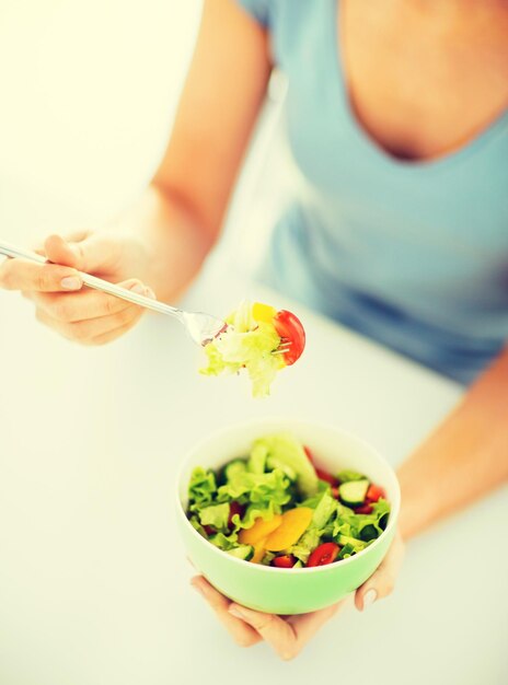 concept d'aliments sains et de cuisine - femme mangeant de la salade avec des légumes