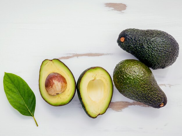 Concept d'aliments sains En gros, avocado frais et feuilles sur un fond blanc en bois déchiqueté Arrière-plan alimentaire avec avocado biologique frais sur une vieille table en bois Espace de mise à plat et de copie