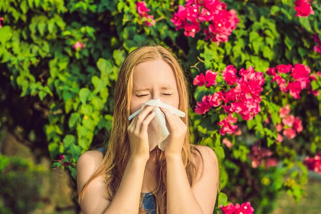 Concept d'allergie au pollen. La jeune femme va éternuer. Arbres en fleurs en arrière-plan.