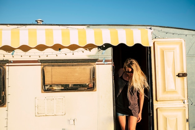 Concept américain de style ancien avec une belle jeune fille blonde sur la porte d'une vieille caravane vintage