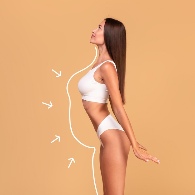 Photo concept amincissant vue latérale d'une femme mince en lingerie blanche avec une forme de corps parfaite posant avec des contours et des flèches