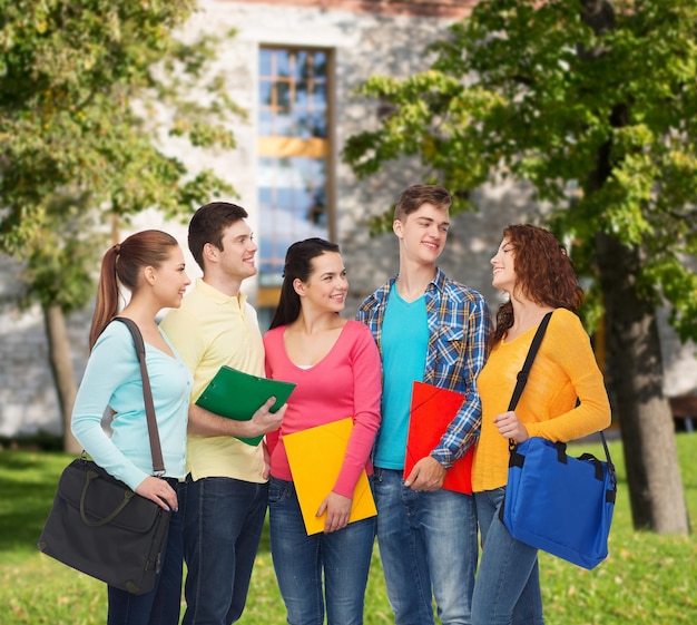 concept d'amitié, d'école, d'éducation et de personnes - groupe d'adolescents souriants avec des dossiers et des sacs d'école sur fond de campus