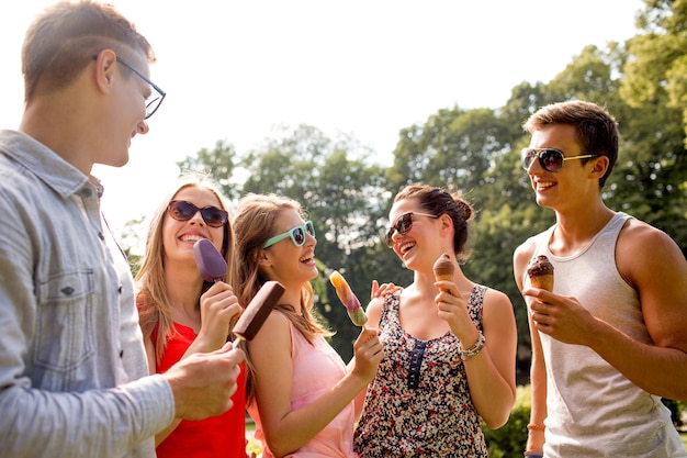 concept d'amitié, de loisirs, de bonbons, d'été et de personnes - groupe d'amis souriants avec de la glace à l'extérieur