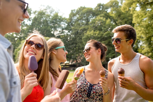 concept d'amitié, de loisirs, de bonbons, d'été et de personnes - groupe d'amis souriants avec de la glace à l'extérieur