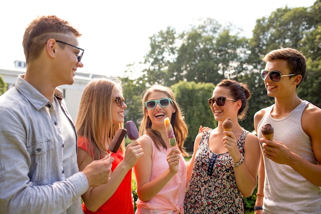 concept d'amitié, de loisirs, de bonbons, d'été et de personnes - groupe d'amis souriants avec de la glace à l'extérieur