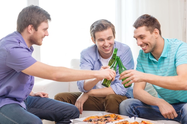 concept d'amitié, de nourriture et de loisirs - amis masculins souriants avec de la bière et de la pizza à la maison