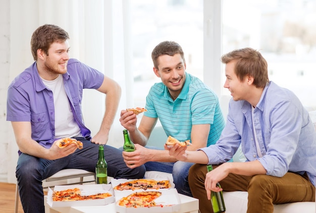 concept d'amitié, de nourriture et de loisirs - amis masculins souriants avec de la bière et de la pizza à la maison