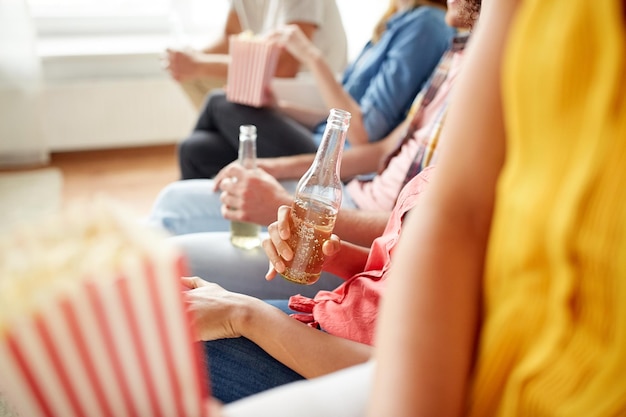 concept d'amitié, de personnes et de divertissement - gros plan d'amis avec du pop-corn et de la bière à la maison