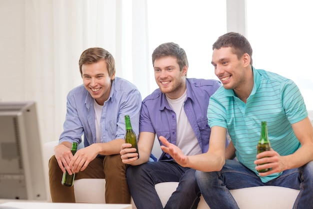 concept d'amitié, de sport et de divertissement - amis masculins heureux avec de la bière en regardant la télévision à la maison