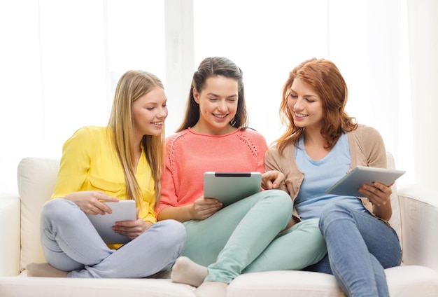 concept d'amitié, de technologie et d'internet - trois adolescentes souriantes avec des ordinateurs tablettes pc à la maison