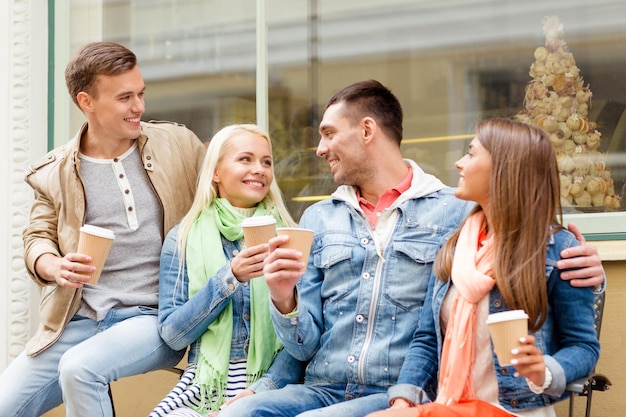concept d'amitié, de voyage, de boisson et de vacances - groupe d'amis souriants avec café à emporter