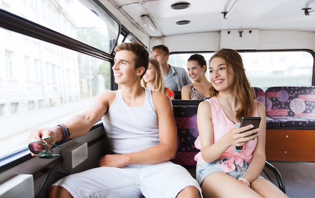 concept d'amitié, de voyage, de vacances, d'été et de personnes - groupe d'amis adolescents heureux avec smartphone voyageant en bus