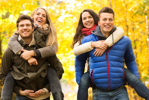 concept d'amour, d'amitié, de famille et de personnes - amis souriants s'amusant dans le parc d'automne