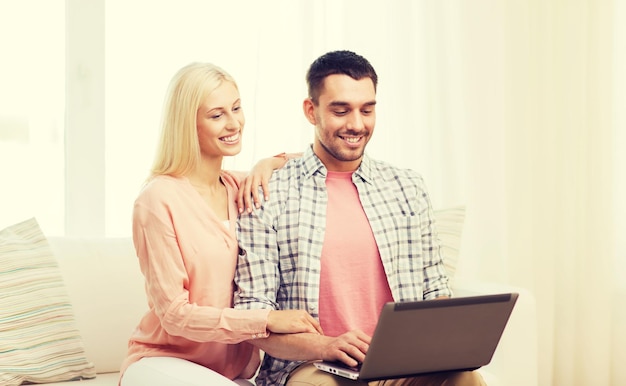 concept d'amour, de famille, de technologie, d'internet et de bonheur - couple heureux souriant avec ordinateur portable à la maison