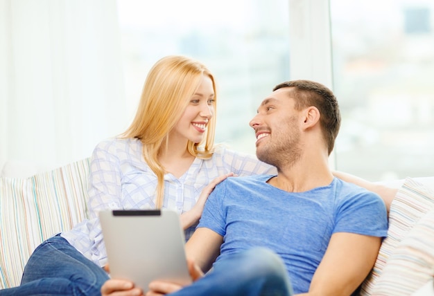 concept d'amour, de famille, de technologie, d'internet et de bonheur - couple heureux souriant avec un ordinateur tablette pc à la maison