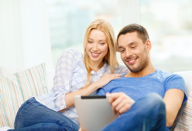 concept d'amour, de famille, de technologie, d'internet et de bonheur - couple heureux souriant avec un ordinateur tablette pc à la maison