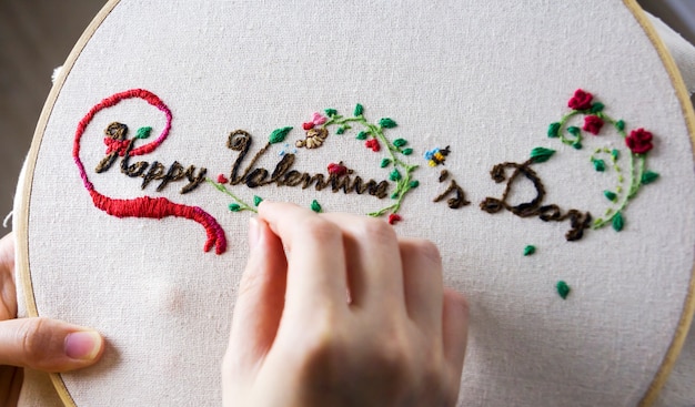 Photo concept de l'amour des mains de la jeune femme sont brodés heureux saint valentin