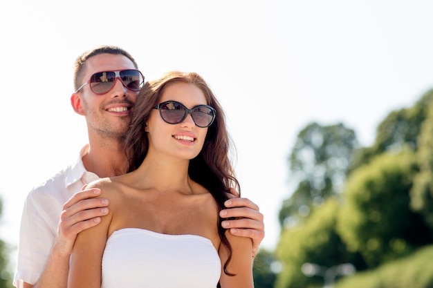 concept d'amour, de mariage, d'été, de rencontres et de personnes - couple souriant portant des lunettes de soleil étreignant dans le parc