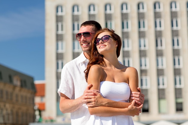 concept d'amour, de mariage, d'été, de rencontres et de personnes - couple souriant portant des lunettes de soleil se serrant dans la ville