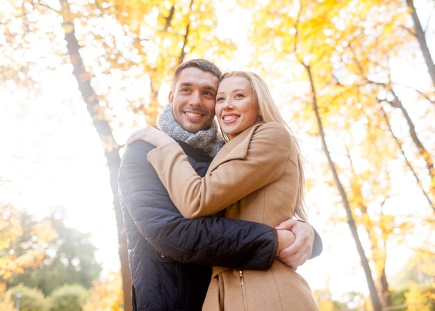 Concept d'amour, de relation, de famille et de personnes - smiling couple hugging in autumn park