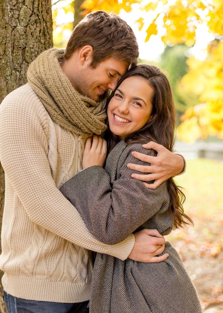 Concept d'amour, de relation, de famille et de personnes - smiling couple hugging in autumn park