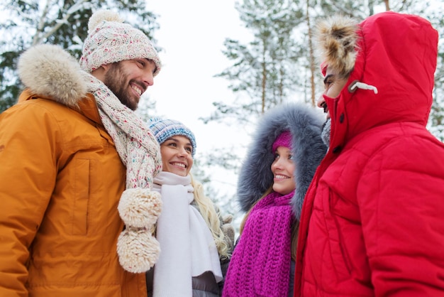 concept d'amour, de relation, de saison, d'amitié et de personnes - groupe d'hommes et de femmes souriants parlant dans la forêt d'hiver