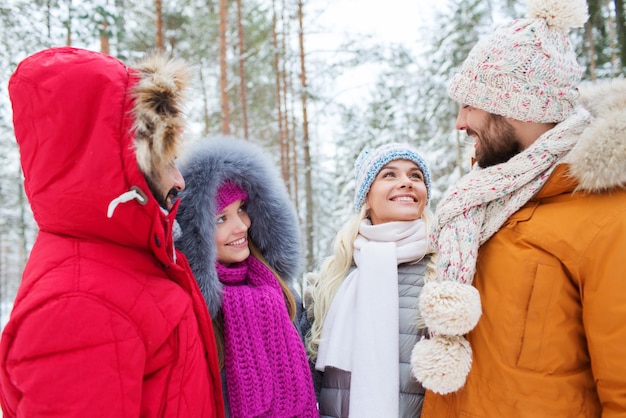 concept d'amour, de relation, de saison, d'amitié et de personnes - groupe d'hommes et de femmes souriants parlant dans la forêt d'hiver