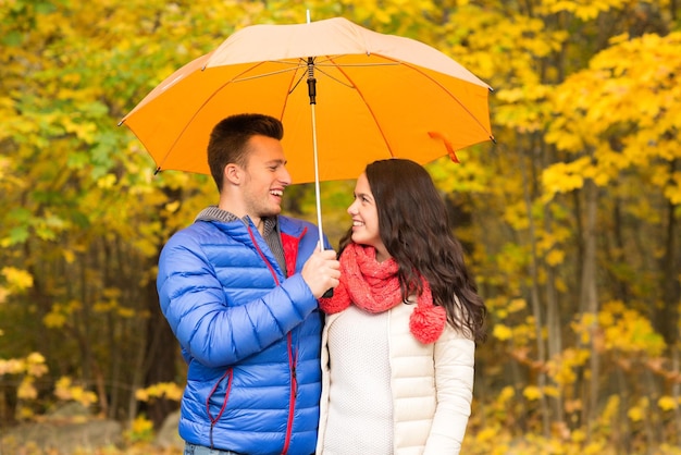 concept d'amour, de relation, de saison, de famille et de personnes - couple souriant avec parapluie marchant dans le parc d'automne