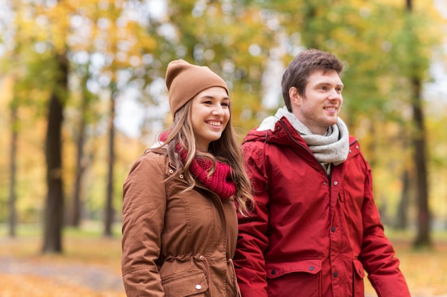 concept d'amour, de relations, de saison et de personnes - heureux jeune couple marchant dans le parc d'automne