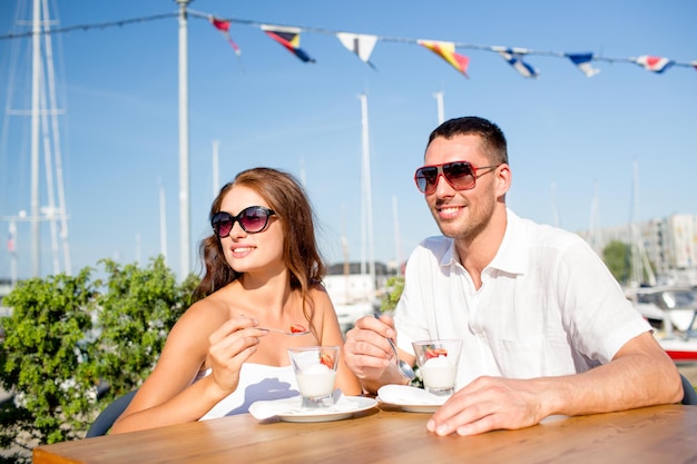 concept d'amour, de rencontres, de personnes et de nourriture - couple souriant portant des lunettes de soleil mangeant un dessert au café