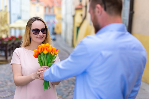 Concept d'amour, de rencontres et de relations - jeune homme donnant des fleurs à sa petite amie ou sa femme