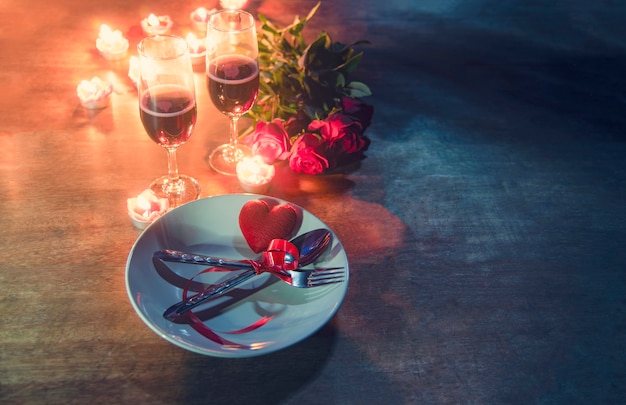 Concept de l&#39;amour romantique dîner Saint Valentin réglage de la table romantique décorée avec cuillère fourchette coeur rouge sur plaque et couple de roses en verre de champagne