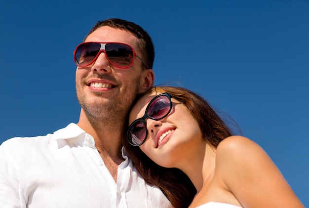 concept d'amour, de voyage, de tourisme, de personnes et d'amitié - couple souriant portant des lunettes de soleil sur fond de ciel bleu