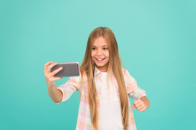 Concept d'appel vidéo Une fille tient un smartphone prenant un selfie Selfie pour les réseaux sociaux Streaming en ligne ou tournage de vlog Bonjour le monde c'est ma chaîne Laissez-moi prendre un selfie Une fille tient un smartphone