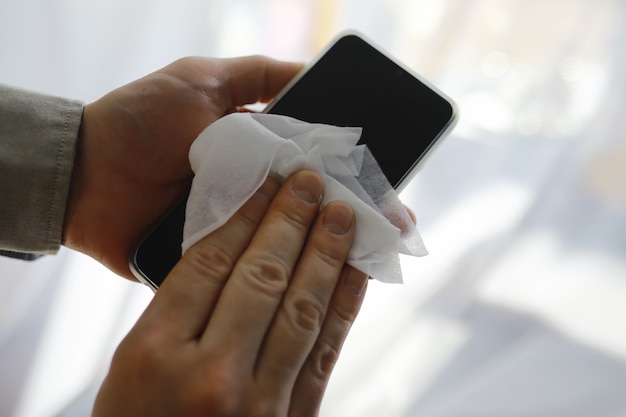 Concept d'apprentissage. Essuyez la saleté des surfaces. Traitement désinfectant de l'écran du téléphone. Traitement sanitaire à domicile en quarantaine.