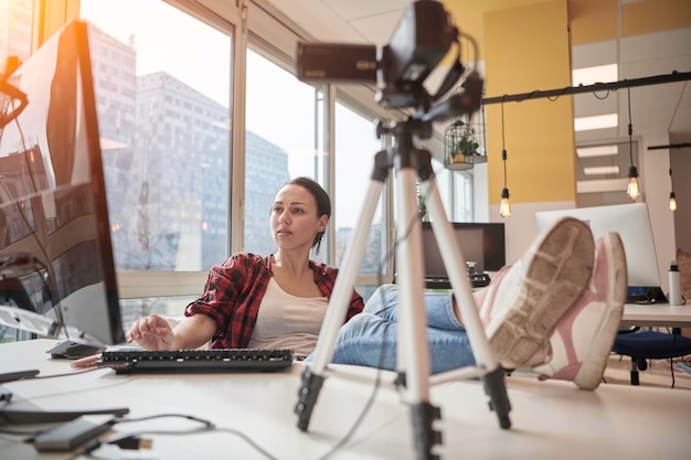 concept d'apprentissage en ligne de l'éducation en ligne avec une jeune étudiante ou une femme d'affaires au bureau filmant avec une caméra à partir d'un trépied