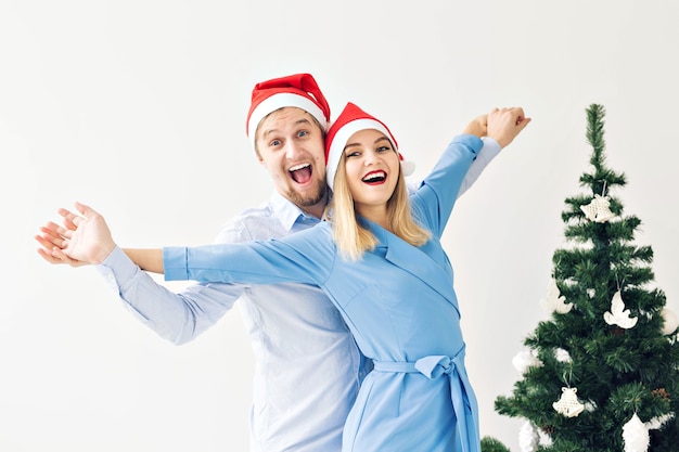 Concept d'arbre de Noël et de vacances - Famille souriante heureuse portant des chapeaux de père Noël célébrant à la maison.