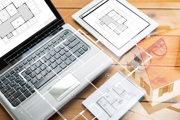 concept d'architecture, d'entreprise et de technologie - gros plan sur un ordinateur portable, une tablette, un ordinateur portable et des lunettes avec un plan de pièce sur une table en bois