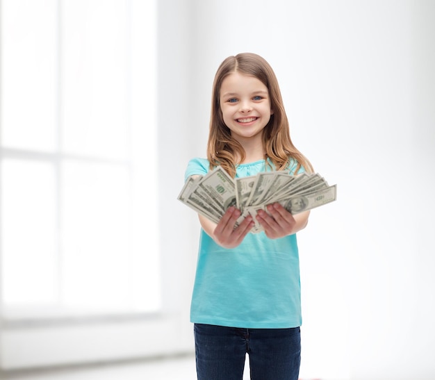 concept d'argent, de finances et de personnes - petite fille souriante donnant de l'argent en dollars