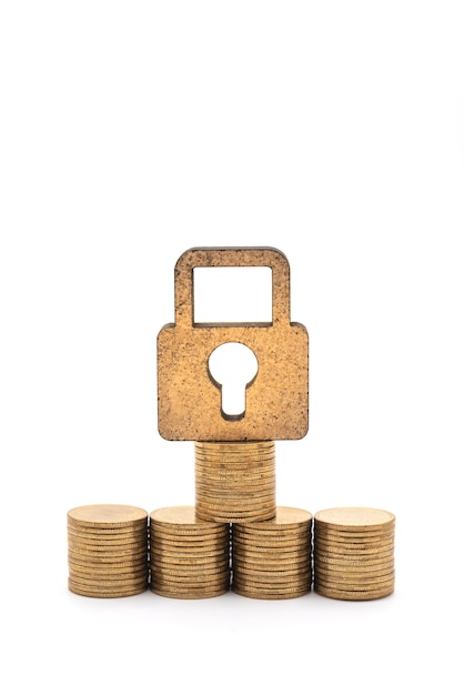 Concept d'argent et de sécurité. Gros plan de l'icône de verrouillage de la clé principale en bois avec pile et pile de pièces d'or sur fond blanc.