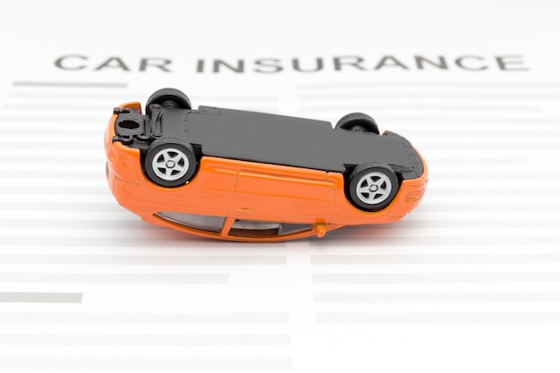 Concept d&#39;assurance automobile avec accident voiture jouet s&#39;allonger sur le bureau.
