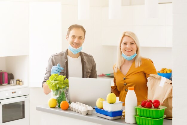 Concept d'auto-isolement. couple déballant un sac en papier avec de la nourriture dans la cuisine, prêt pour la quarantaine lors d'une épidémie