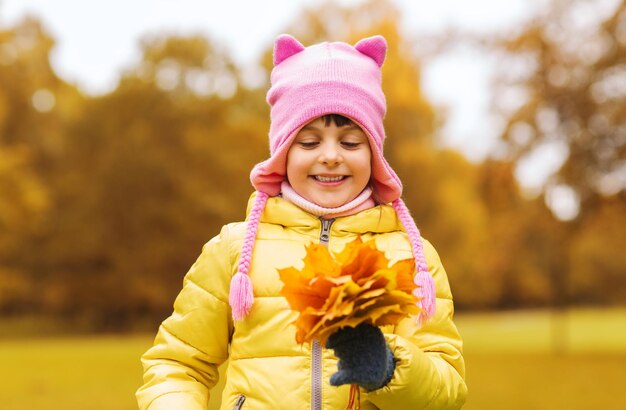 concept d'automne, d'enfance, de bonheur et de personnes - belle petite fille heureuse avec un bouquet de feuilles d'érable à l'extérieur