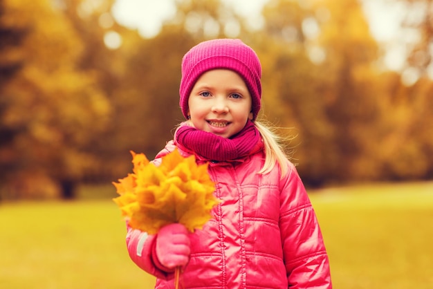 concept d'automne, d'enfance, de bonheur et de personnes - belle petite fille heureuse avec un bouquet de feuilles d'érable à l'extérieur