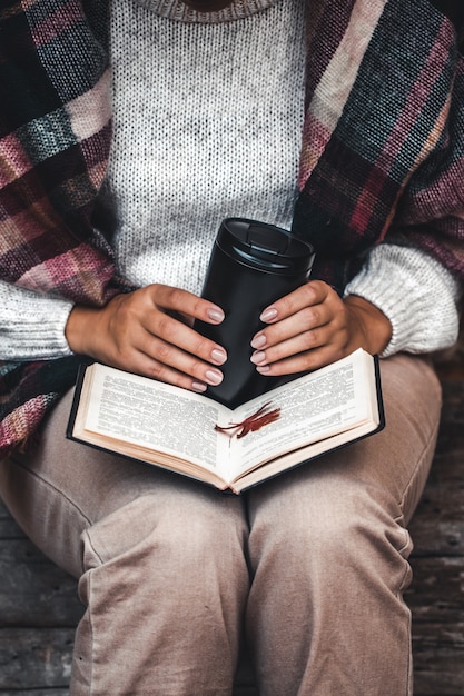 Photo concept d'automne, un livre ouvert entre les mains d'une fille aux feuilles jaunes