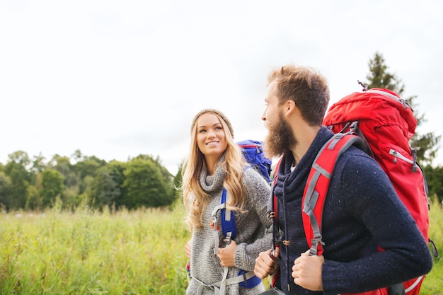 concept d'aventure, de voyage, de tourisme, de randonnée et de personnes - couple souriant marchant avec des sacs à dos à l'extérieur