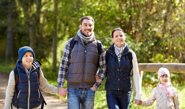 concept d'aventure, de voyage, de tourisme, de randonnée et de personnes - famille heureuse marchant avec des sacs à dos dans les bois